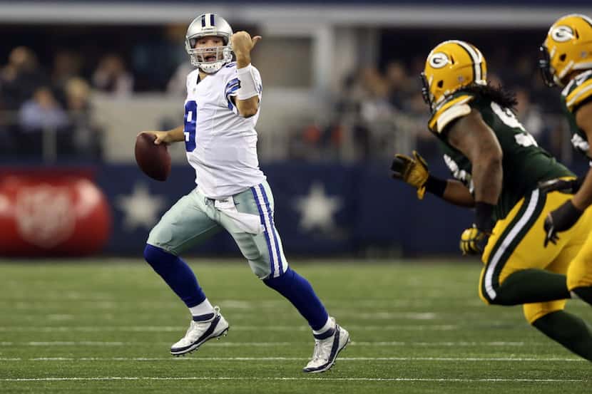Dallas Cowboys quarterback Tony Romo (9) signals to a receiver as he is pressured by the...