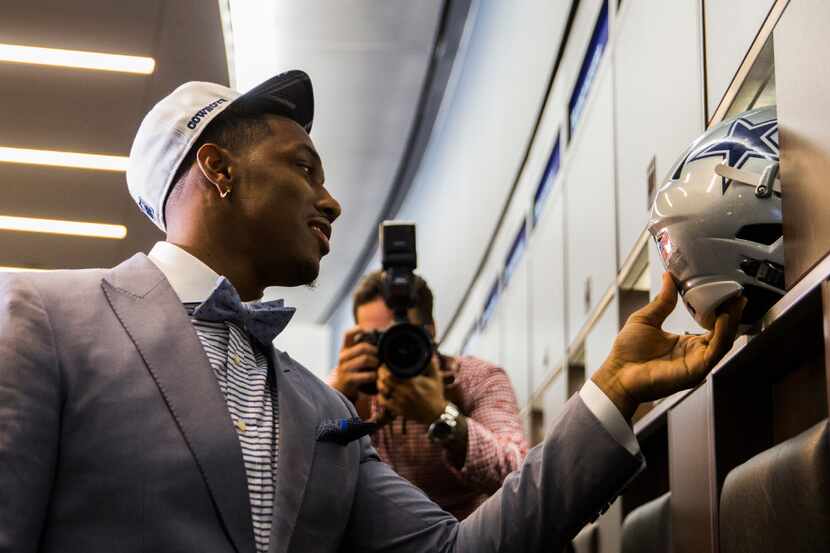 The Dallas Cowboys first round draft pick, defensive end Taco Charlton, looks at his helmet...