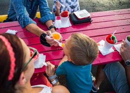 Lucas Harless, 4, gets a taste of a snow cone from his grandfather Tim Harless at TC Shaved...