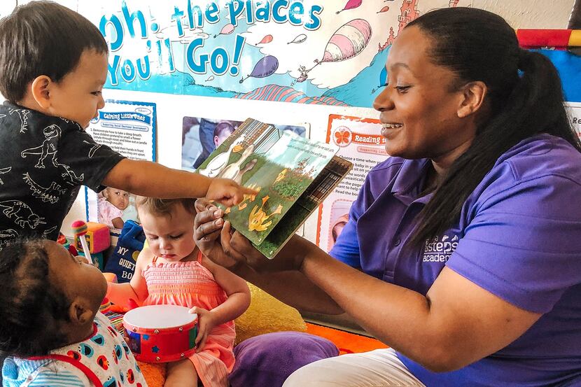 Woman shows a picture book to young children.