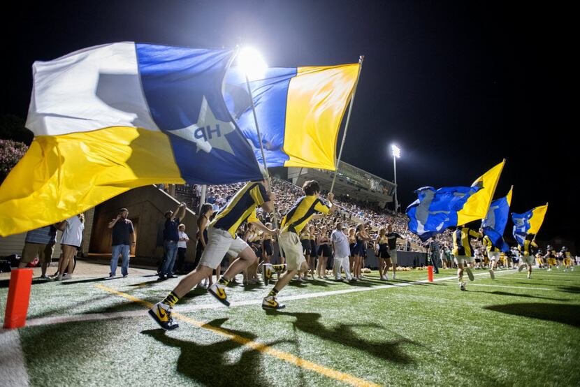 The Highland Park Scotsmen spirit squad carry flags down the sideline to celebrate a...