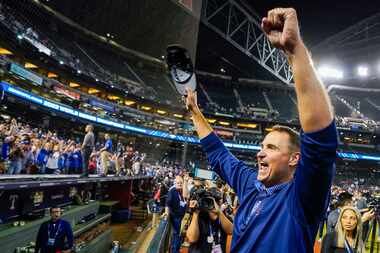 Texas Rangers general manager Chris Young yells to fans as Rangers players celebrate after...