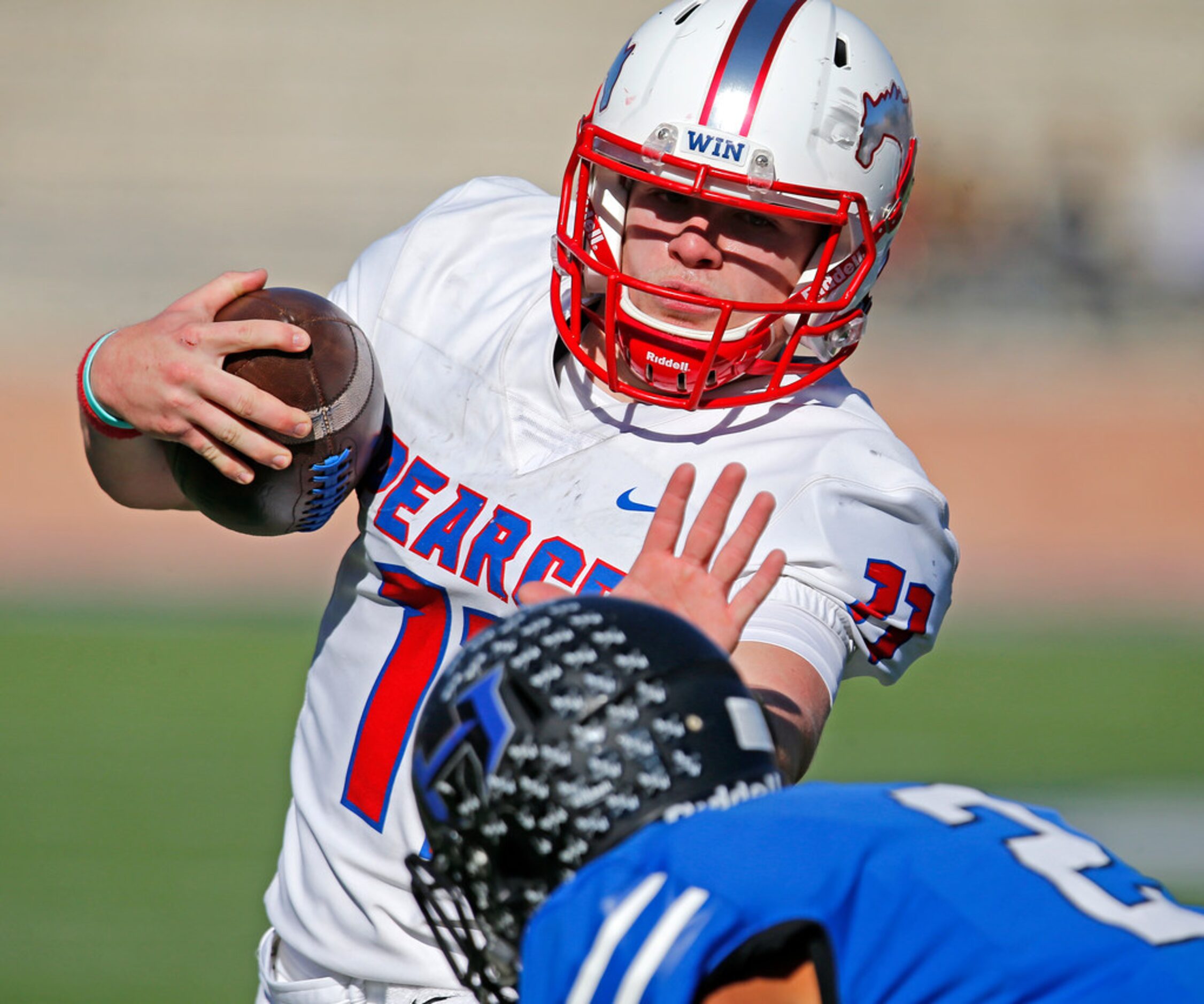 Pearce High School quarterback Bo Brewer (11) stiff arms Hebron High School defensive back...