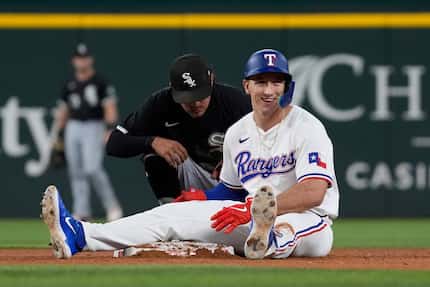 Texas Rangers' Wyatt Langford, right, smiles after sliding safely into at second base...