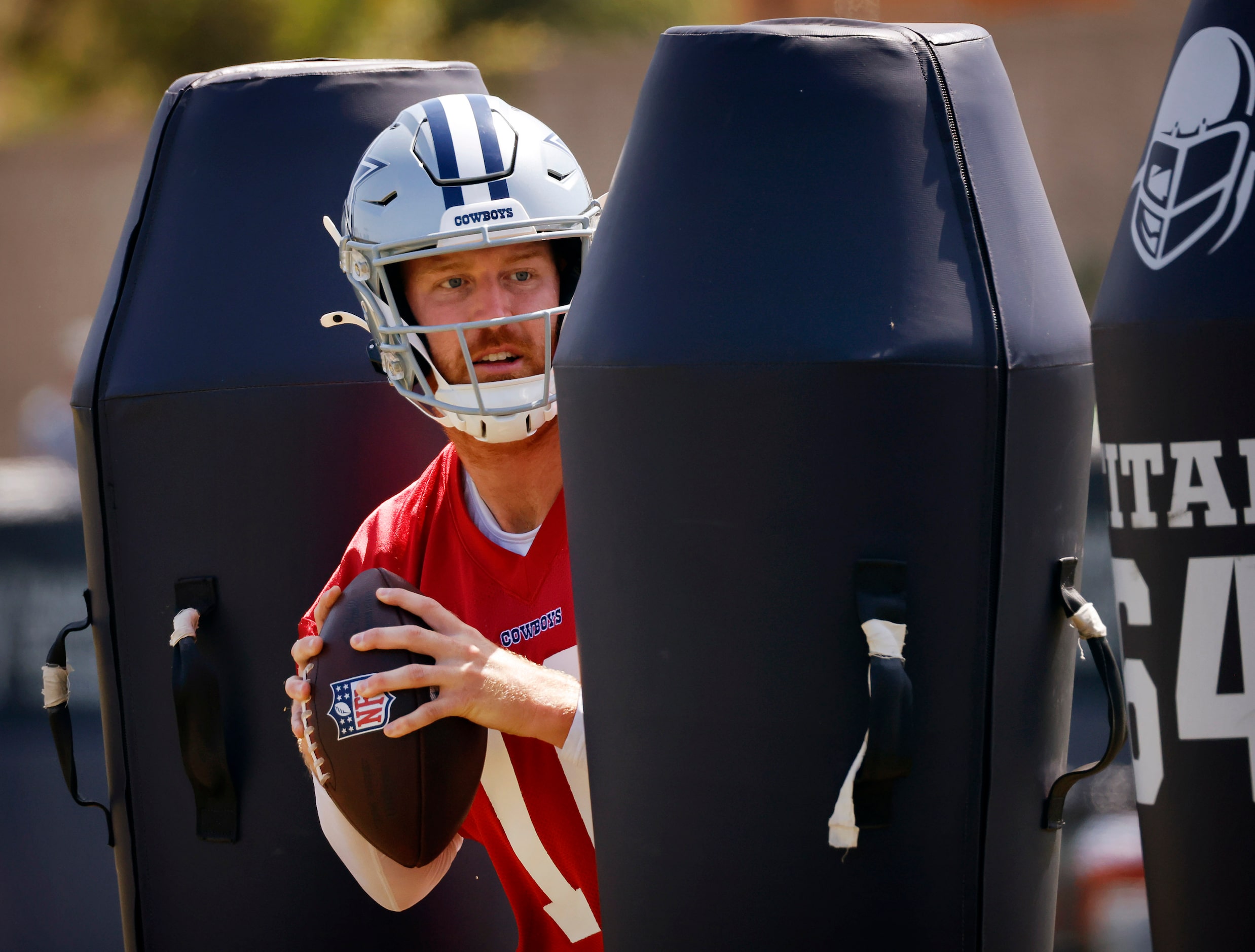 Dallas Cowboys quarterback Cooper Rush (10) dodges the blocking dummies at training camp...