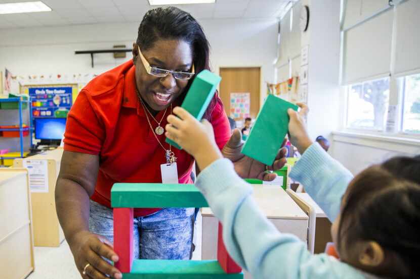 Substitute Teacher Aid Alicia Pyle helps a pre-kindergarten student to build a block tower...