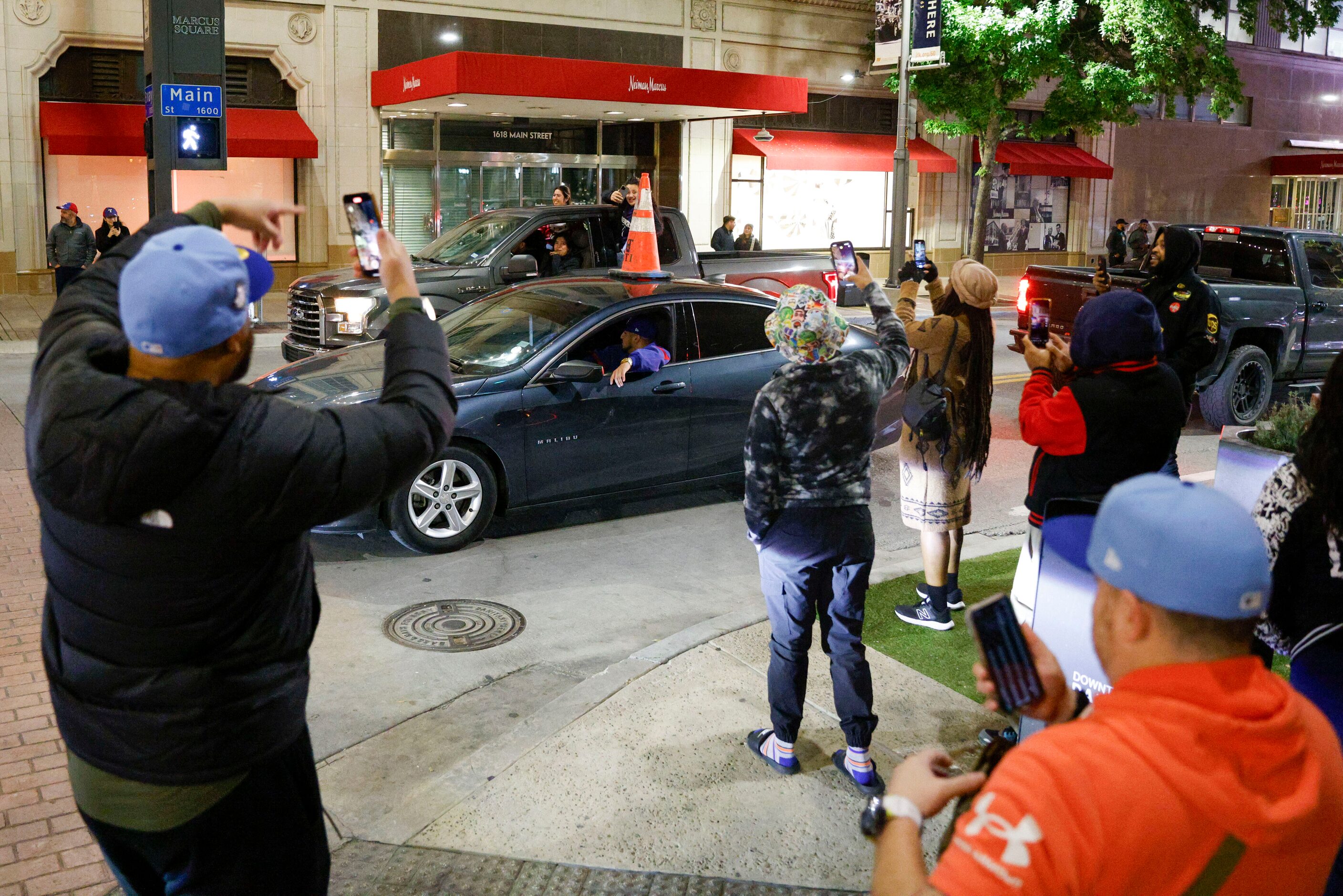 People take photos and videos as a car drives backwards along Main Street celebrating the...