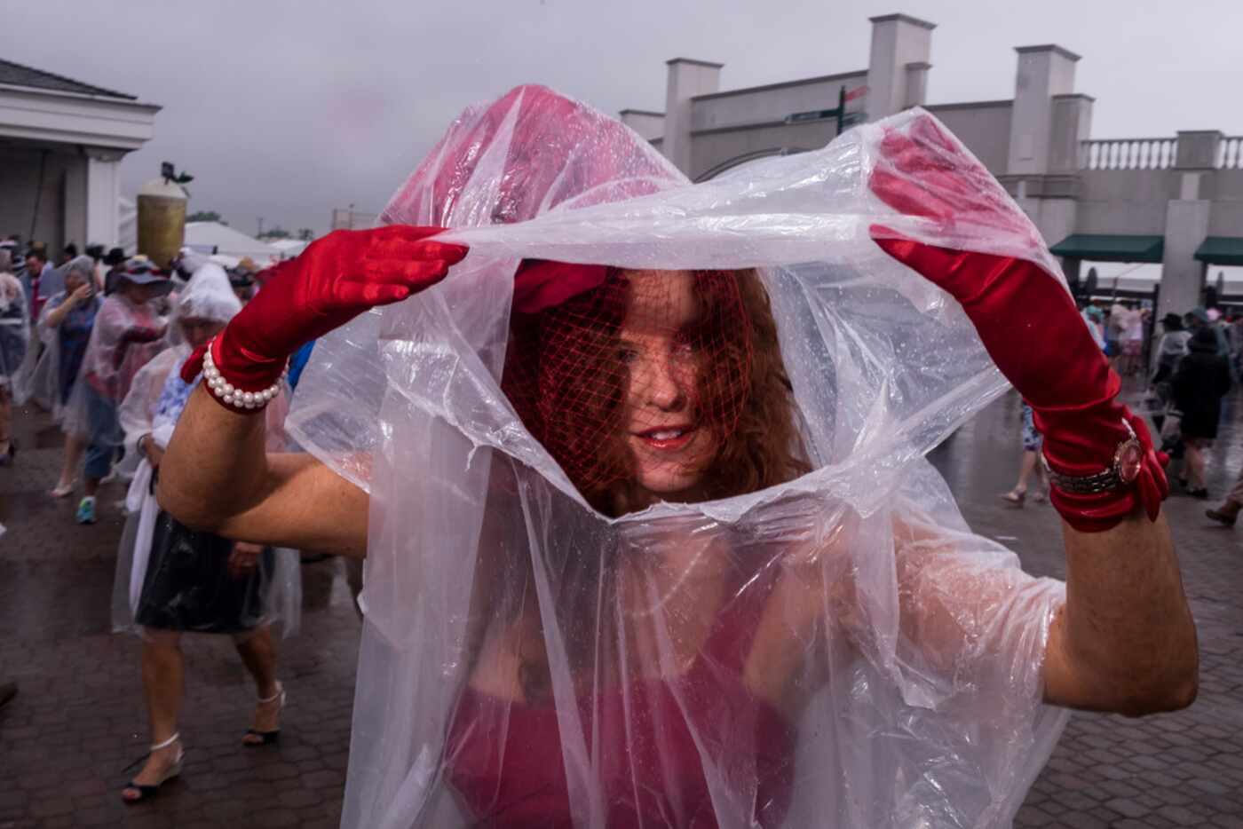A reveler protects her derby hat from the rain with a poncho during the Kentucky Derby in...