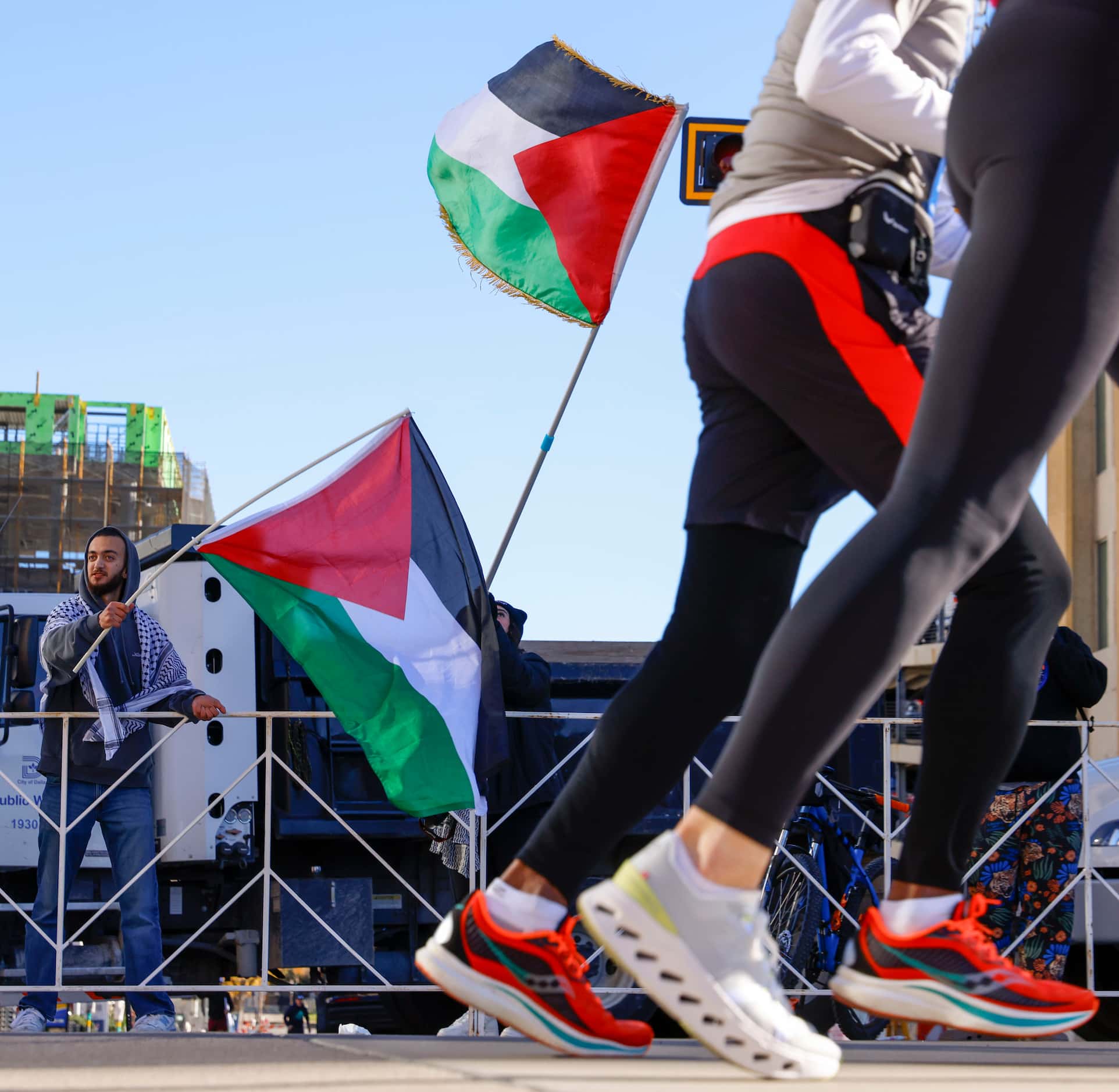 Dallas Muslim Running Club members waving Palestinian flag cheer for the runners during 2023...