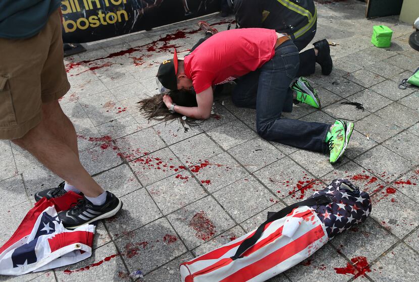 A man tries to comfort a victim near the scene of the first explosion near the finish line...