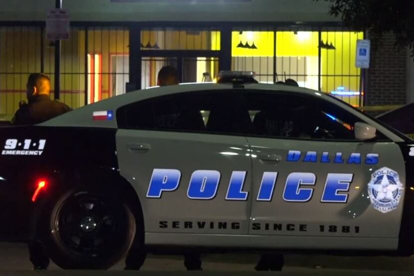 Dallas police officers stand outside a business near were a shooting victim was found Friday...