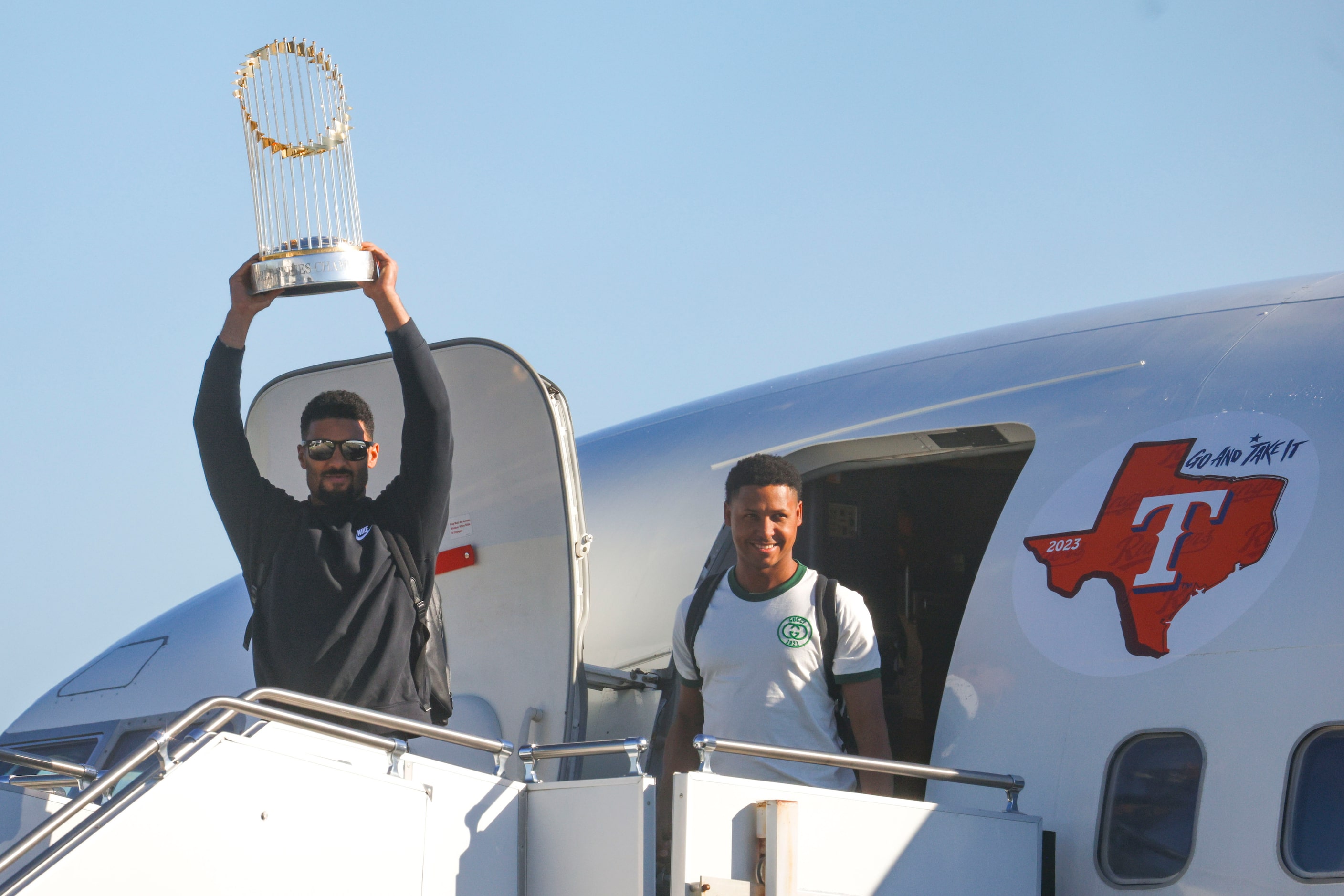 Texas Rangers’ Marcus Semien hoists the Commissioner's Trophy by pitcher José Leclerc upon...