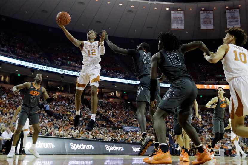 Texas guard Kerwin Roach II (12) shoots past Oklahoma State forward Yor Anei (14) during the...