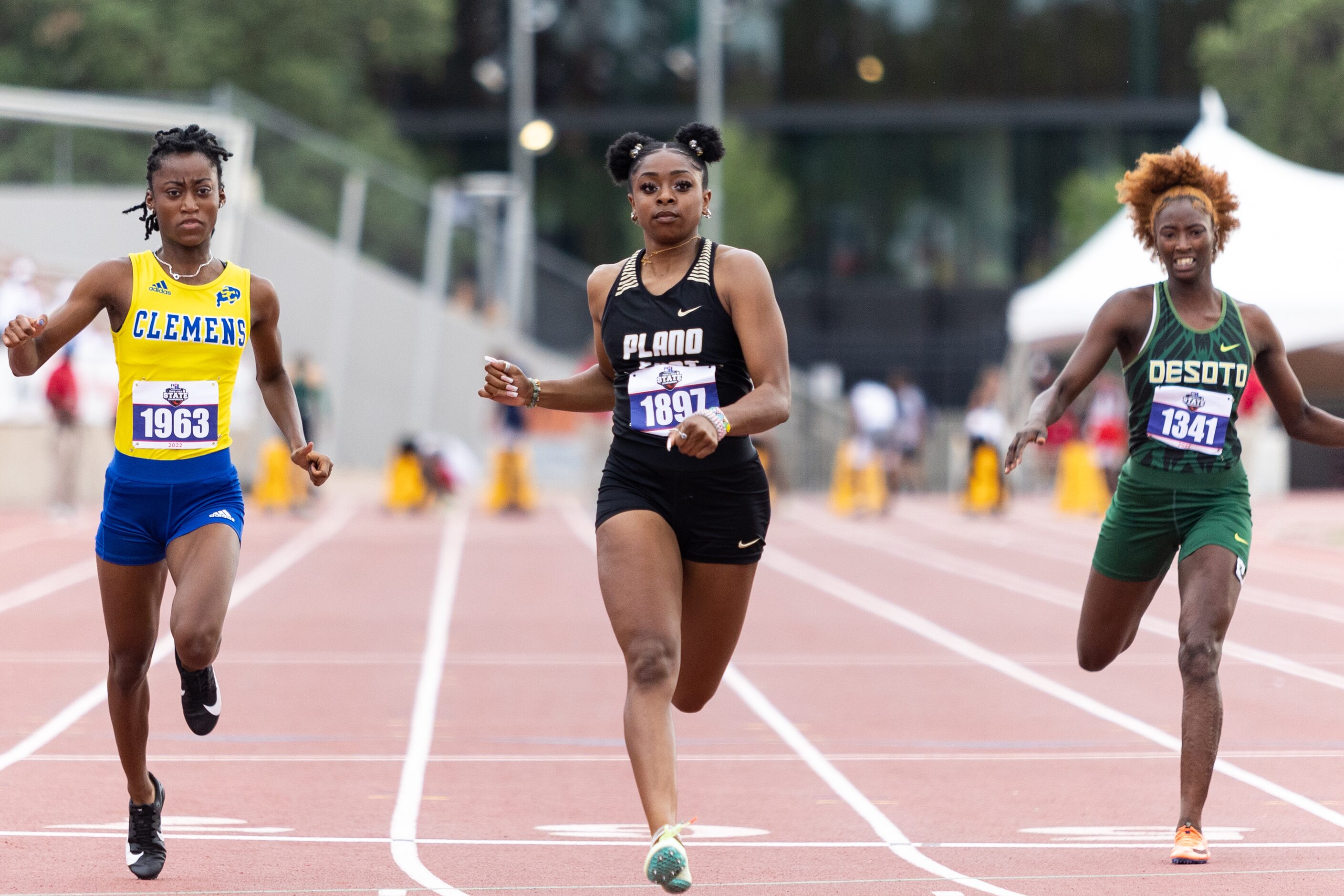 Tiriah Kelley of Plano East, center, crosses the finish in the girls' 100-meter dash at the...