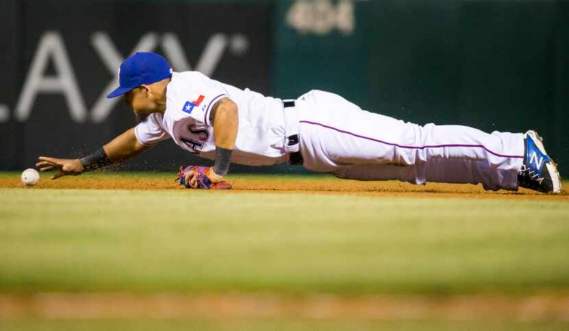Texas Rangers second baseman Rougned Odor dives to pick up a ball hit by Seattle Mariners...