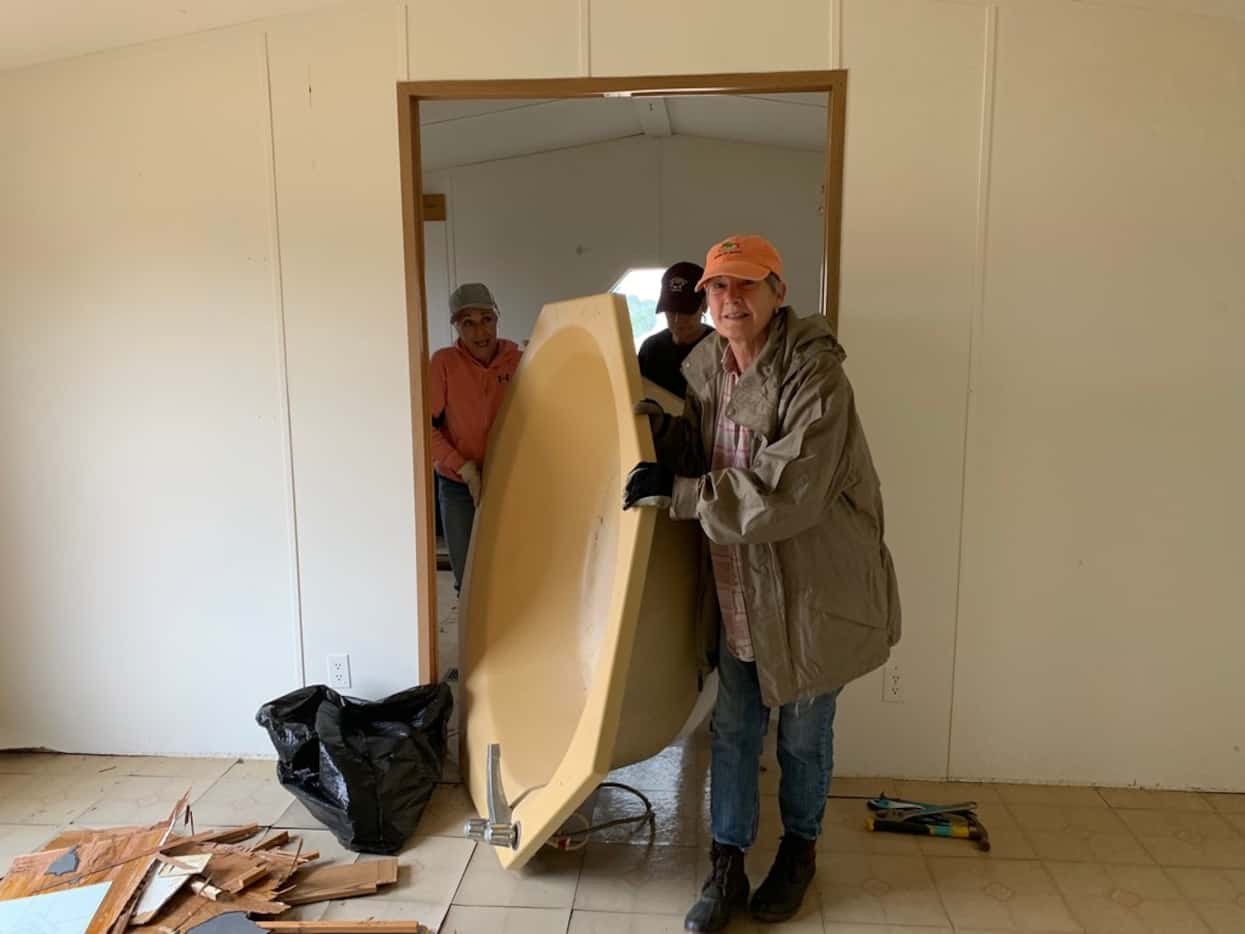 Carolyn Burns (in front) tackles removing a bathtub with friends from her church. Only one...