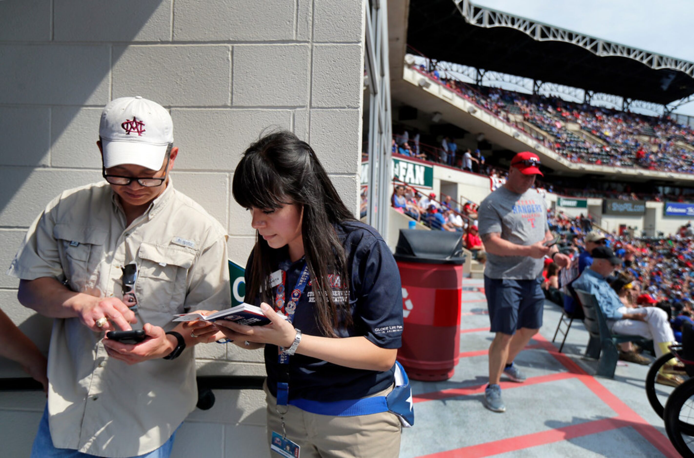 Texas Rangers usher Margarita Aguirre (right) helps fan Leland Tieh of Frisco find his...