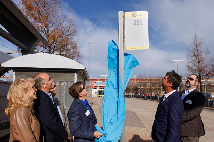 Carrollton Mayor Kevin Falconer unveils a new bus stop sign alongside local city officials...