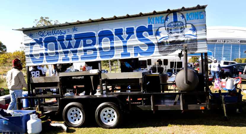 An elaborate hand-painted signs stands over the grill as Cowboys fans tailgate before the...