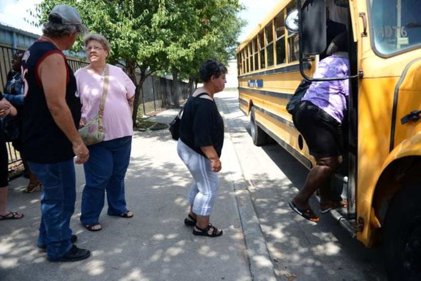 
Homeless at Austin Street Center wait to board a bus that will take them to an evening...