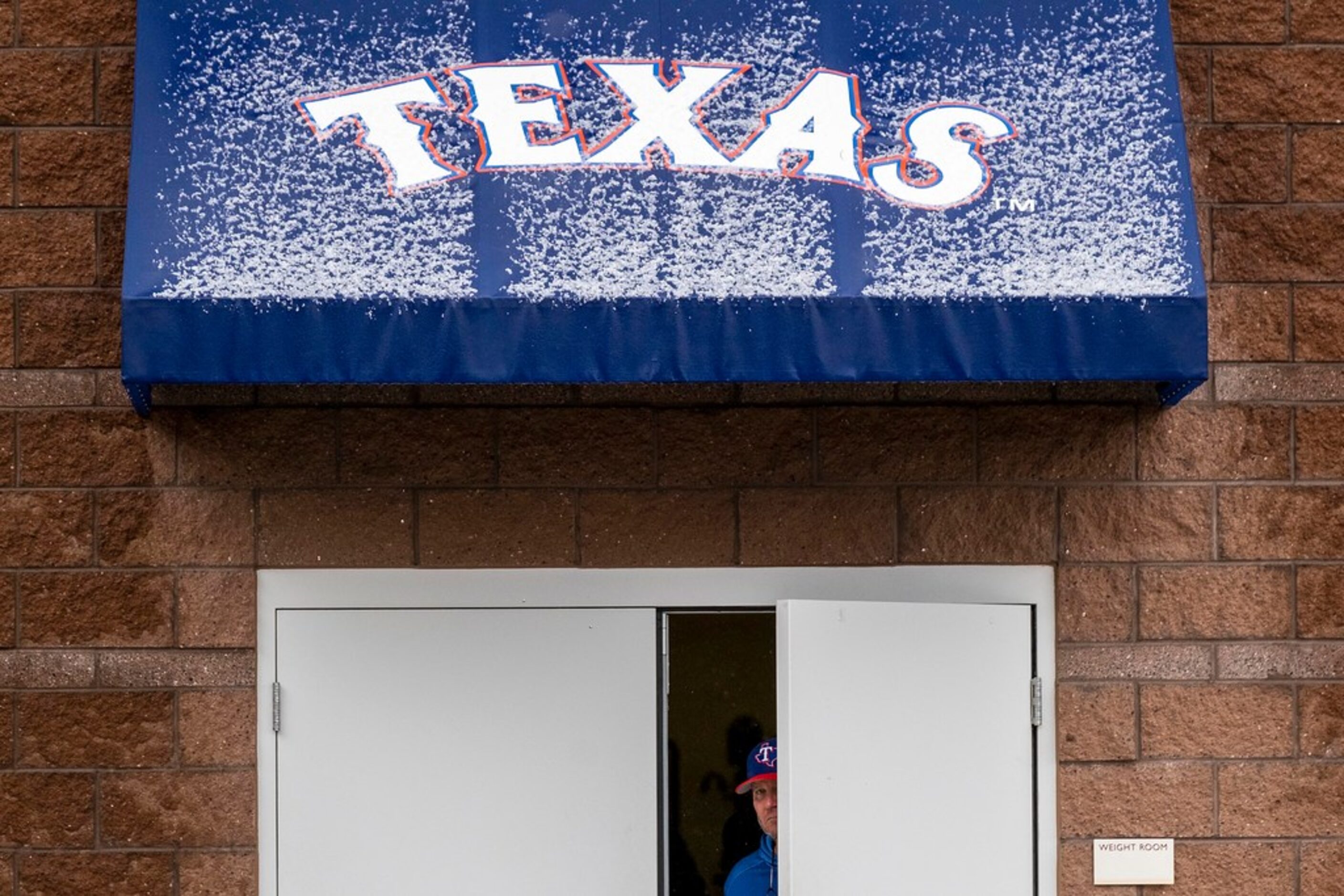 Snow pellets collect on an awning over the door to the Texas Rangers weight room following a...