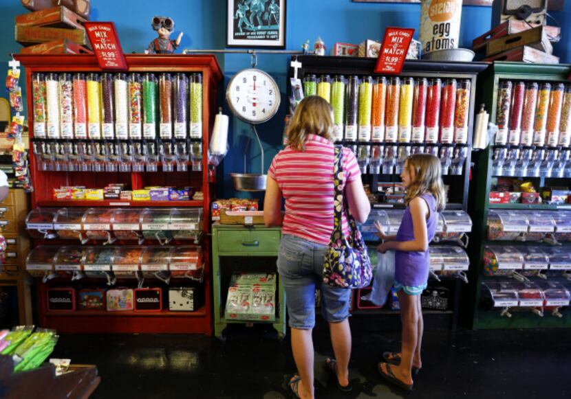 Customers make selections from bins and bins of candy lining the wall at Atomic Candy in...