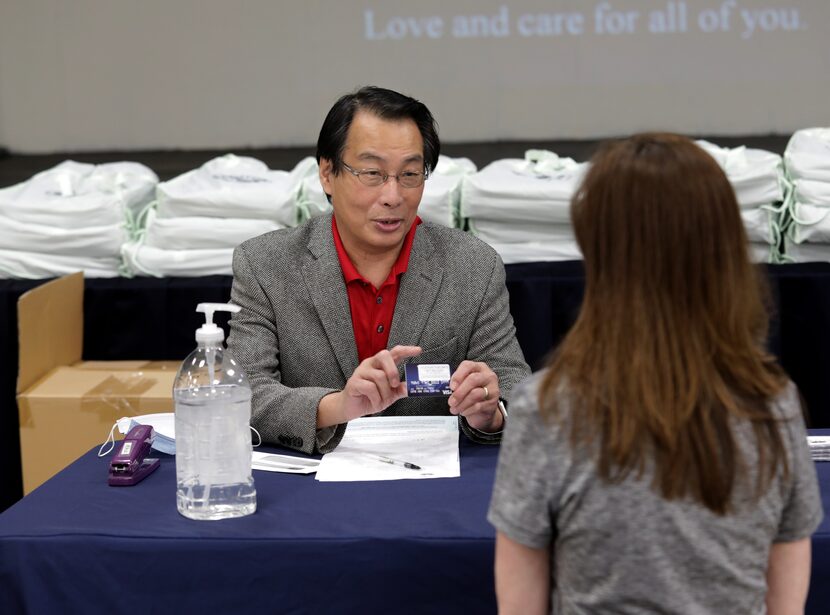 Addison mayor Joe Chow, left, displays a pre-paid giftcard to Tia Bourne.  The cards are...