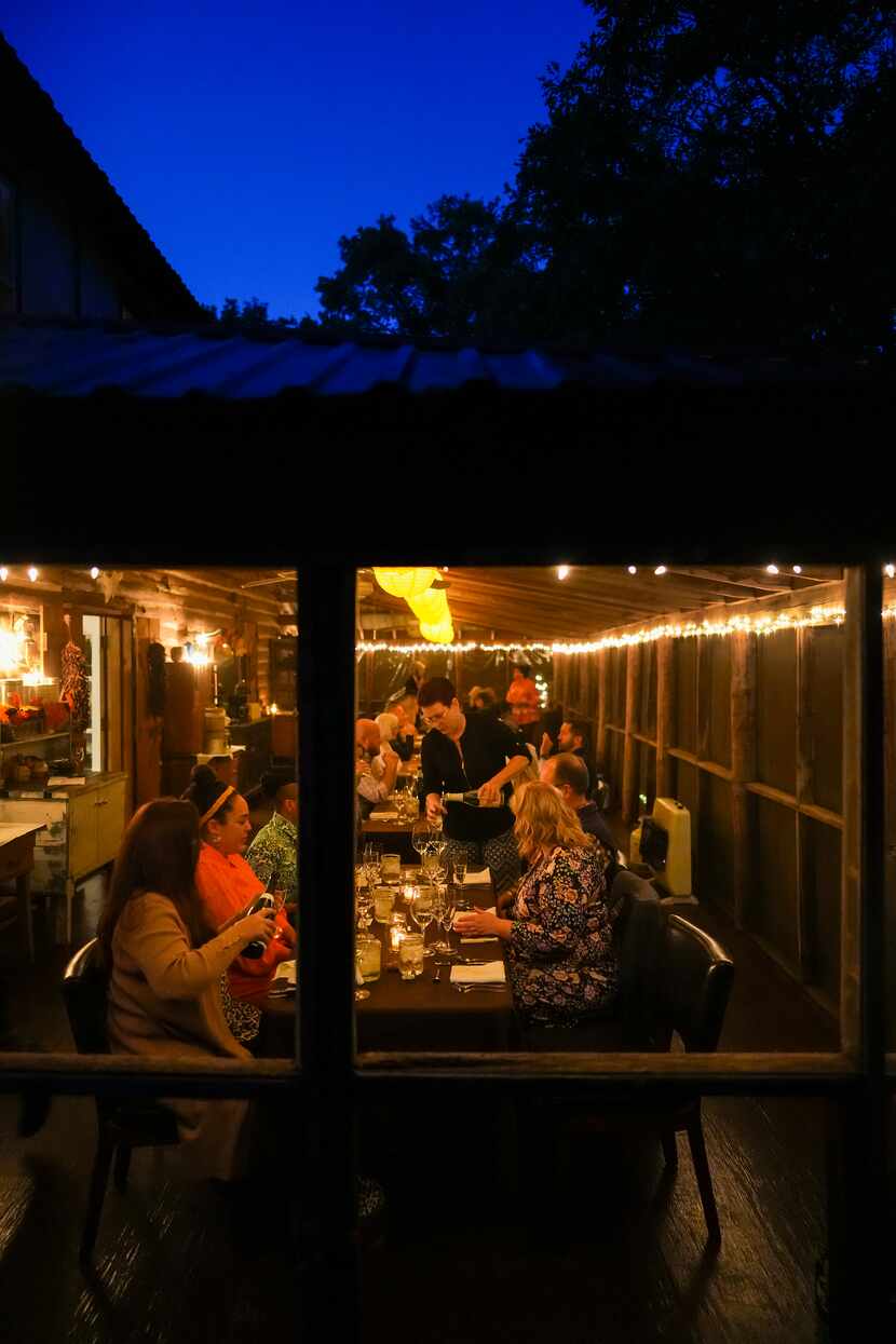 Guests pour their own bring-your-own-wine during a dinner on the screened-in back porch of a...