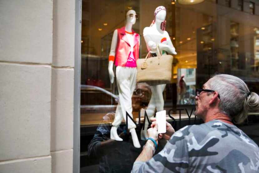 
Ray Souders adds decals to a window display at Neiman Marcus’ flagship store in downtown...