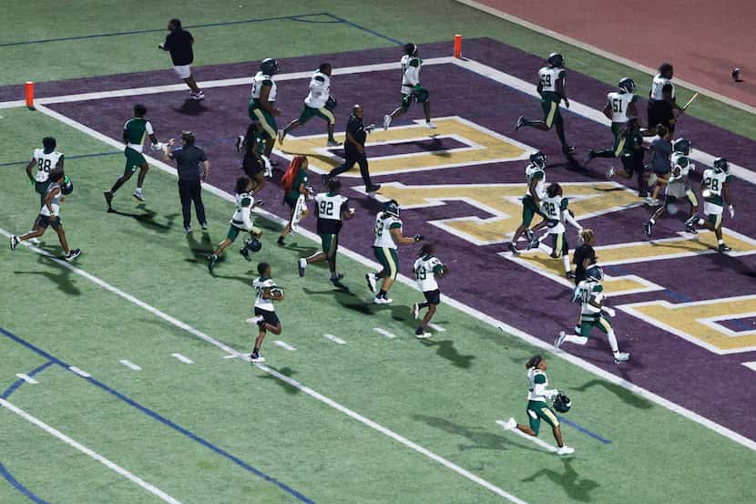 DeSoto players run from the field towards the locker room after a disturbance in the stands...