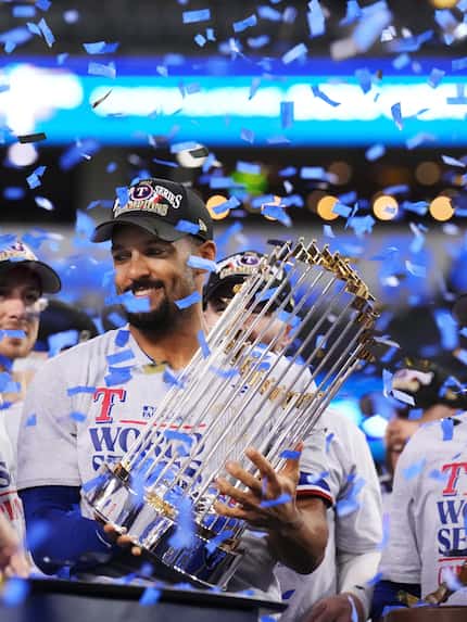 Texas Rangers second baseman Marcus Semien lifts the Commissioner’s Trophy after winning the...