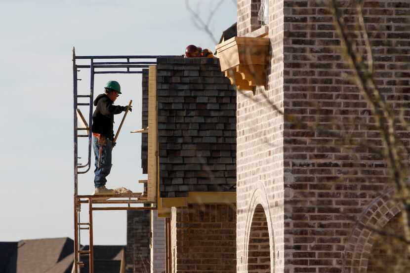 A masonry worker helps put bricks on a house under construction in the Barcelona...