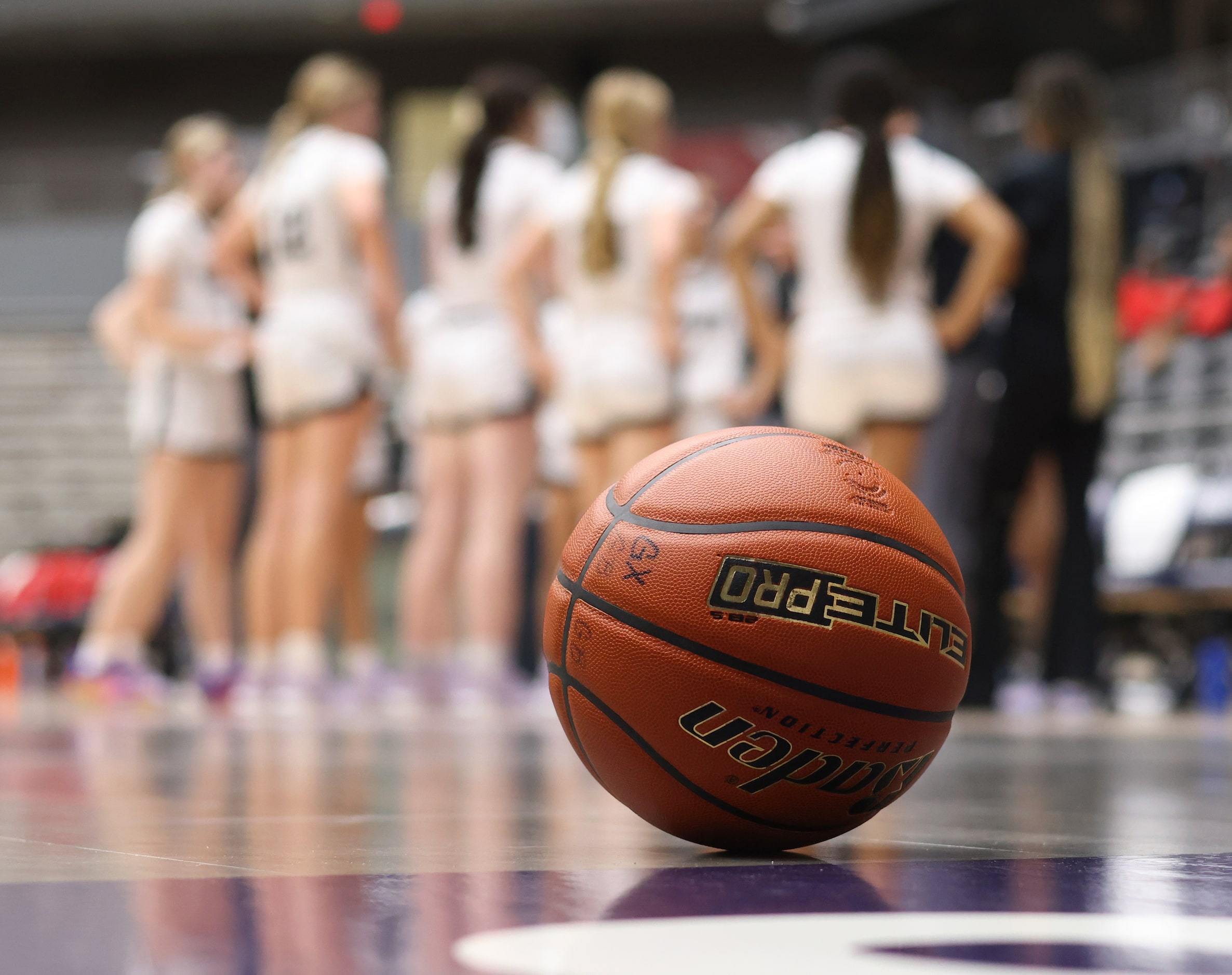 The game ball rests on the baseline as Denton Guyer players huddle during a first quarter...