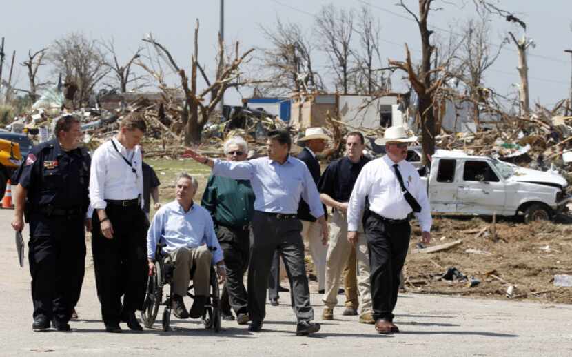 Then-Gov. Rick Perry, center, and then-Attorney General Greg Abbott -- shown inspecting...