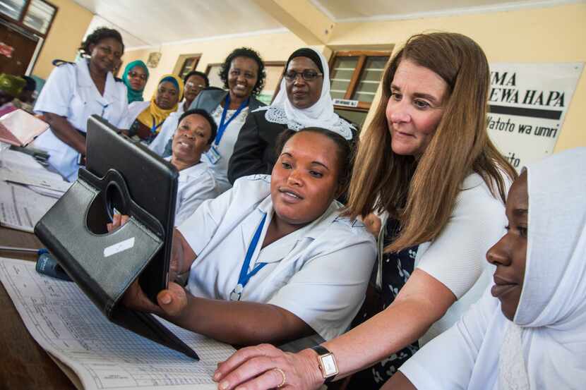 Nurse Chesca Mbilinyi and Melinda Gates try the new digital system to find records of...