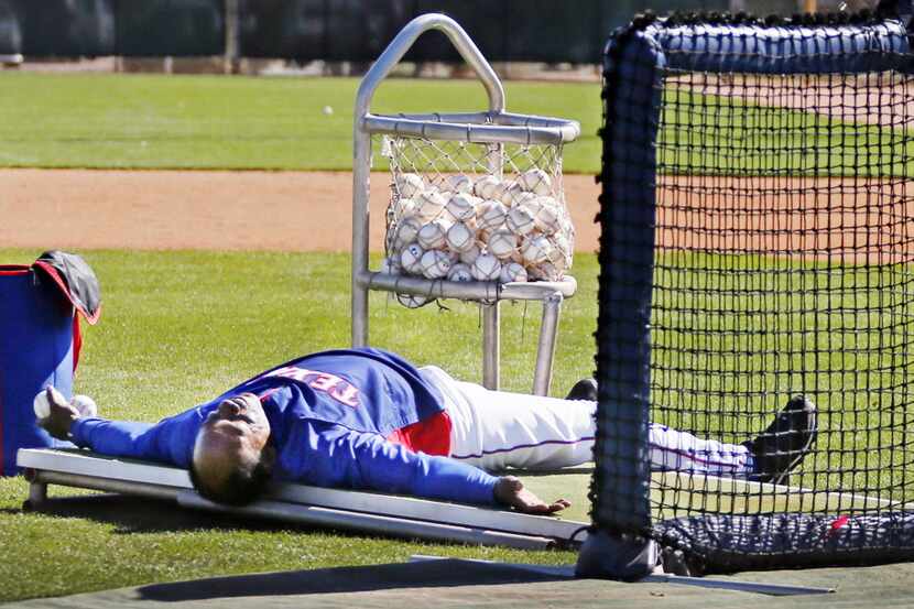 Texas Rangers manager Ron Washington lies down on the mound after almost getting hit by a...