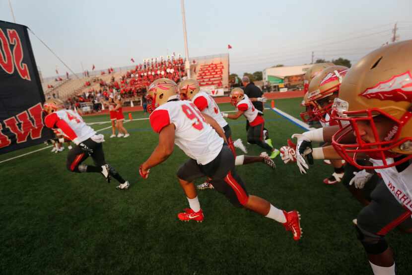 South Grand Prairie players rush the field prior to a high school football game against...