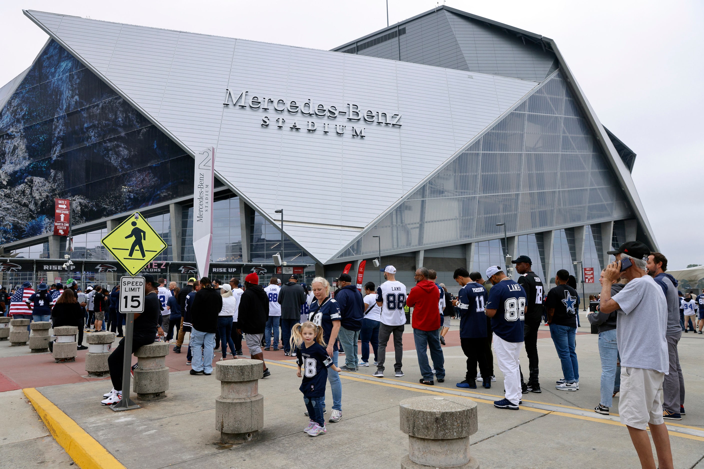 Football fans wait to enter Mercedes-Benz Stadium before a game between the Dallas Cowboys...