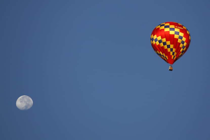 A hot air balloon flies over Plano during a balloon festival at Oak Point Park in Plano,...