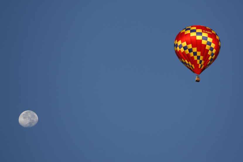 A hot air balloon flies over Plano during a balloon festival at Oak Point Park in Plano,...