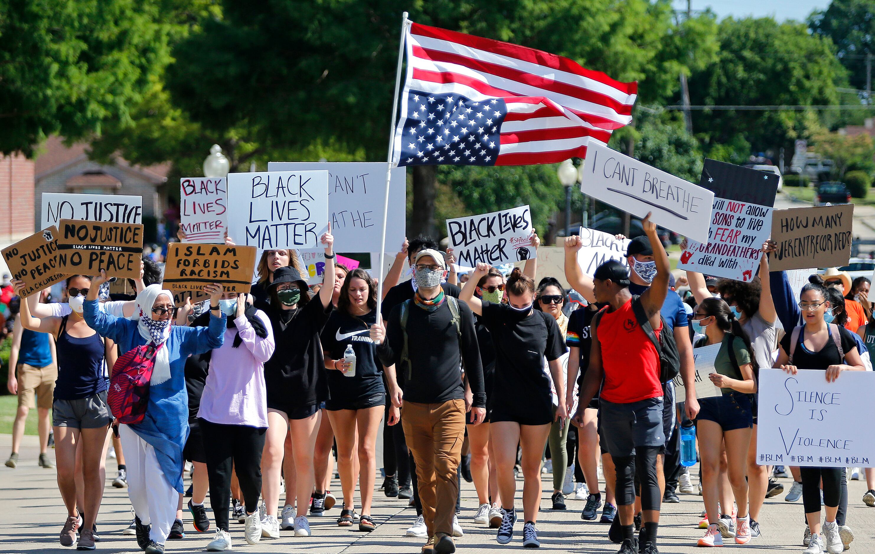 Protesters march beside the Plano Police Department at a protest organized by Our Revolution...