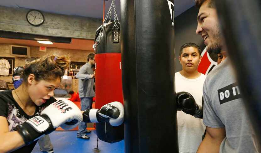 Rafael (right)  watches as Hillary Perez uses a punching bag at Reyes Boxing Club. Like...