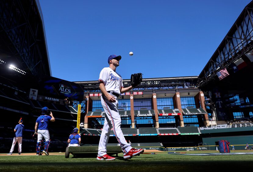 Texas Rangers starting pitcher Max Scherzer tosses the baseball as he waits for fielding...