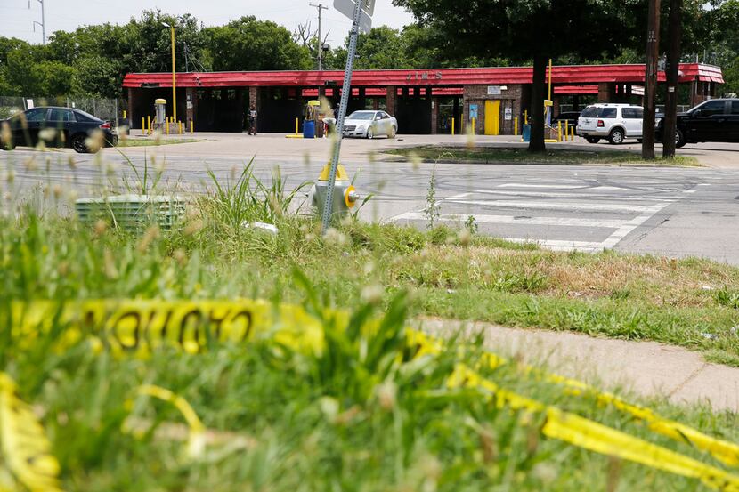 Caution tape lies on the ground across the street from Jim's Car Wash in Dallas on Monday,...
