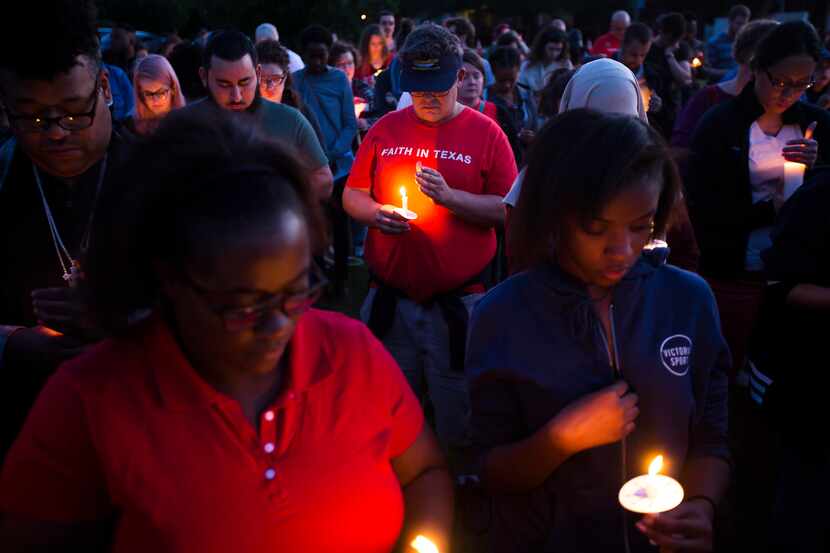 Attendees try to keep their candles lit against the wind during the "Remember His Name:...
