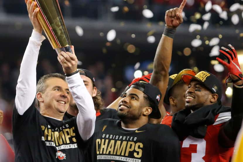 Ohio State head coach Urban Meyer hoists the national championship trophy as running back...