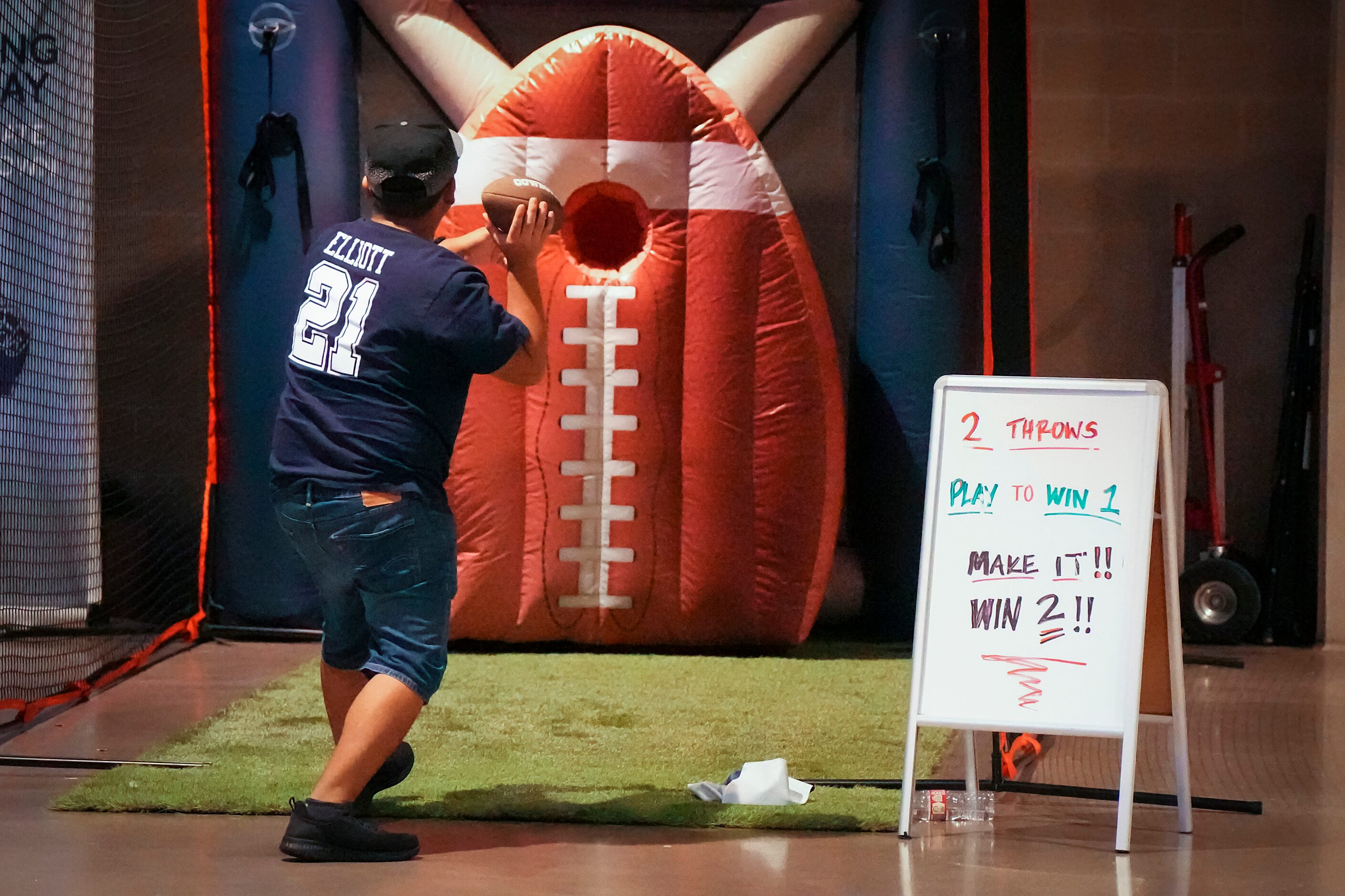 A fann tosses a football at a booth on the concourse during a Dallas Cowboys training camp...