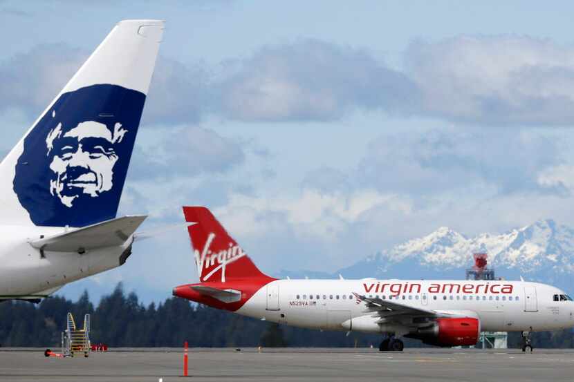  A Virgin America plane taxis past an Alaska Airlines plane waiting at a gate at...