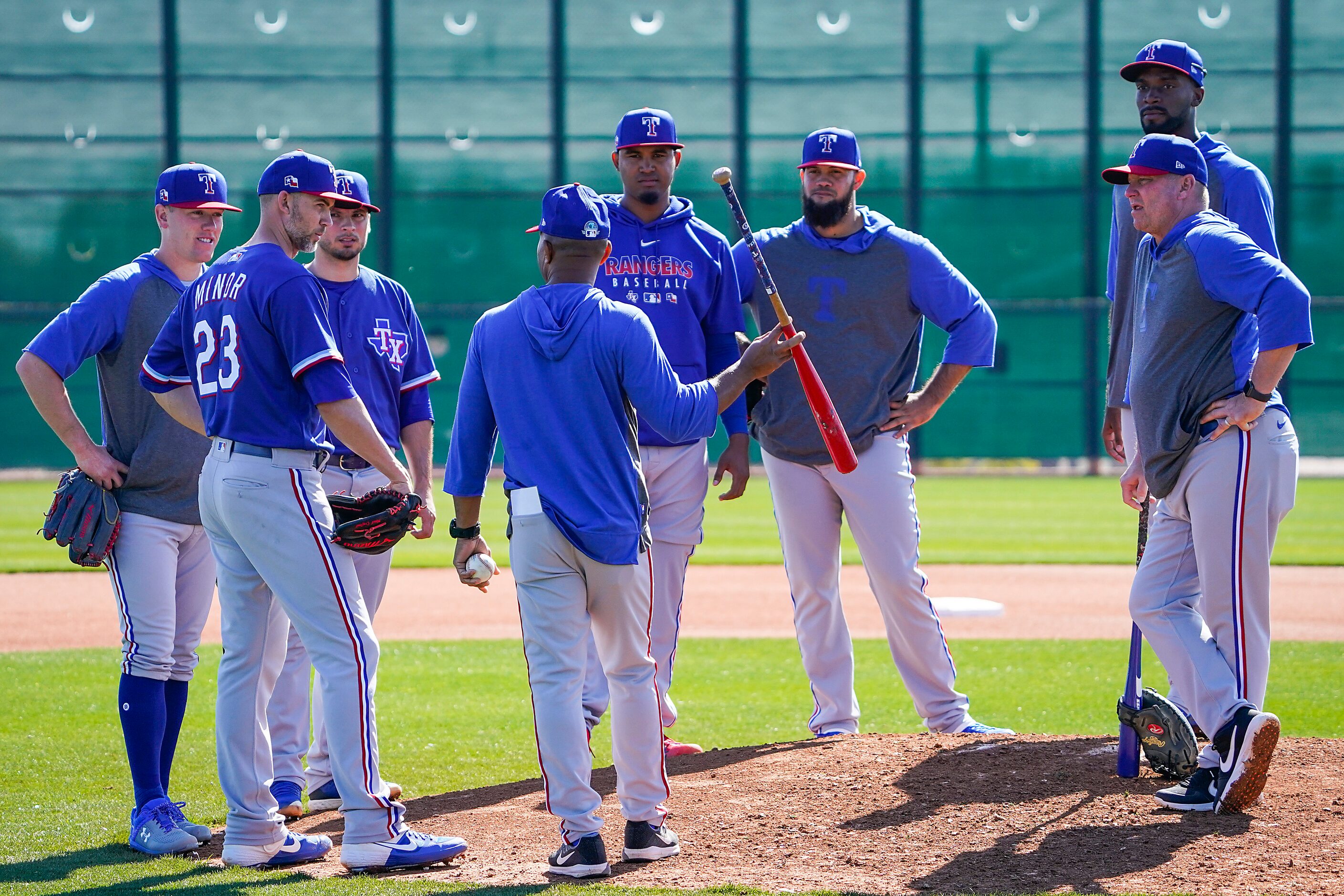 Texas Rangers third base coach Tony Beasley (with bat) talks with pitchers, from left, Kolby...