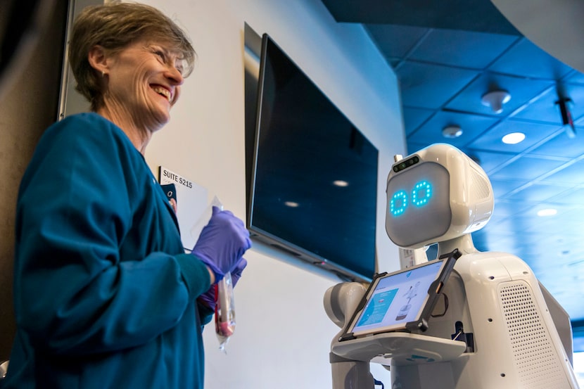 Medical technician Judy Erbacher retrieves a sample product from Moxi, a care assistant...